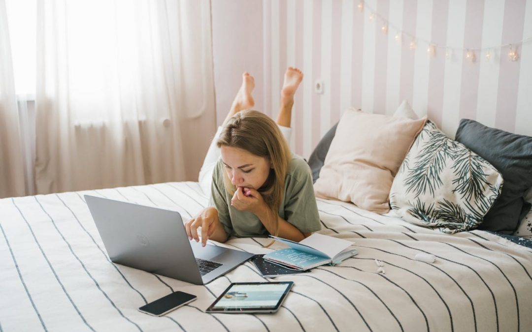 Woman laying On her Bed Working at making Money on her laptop freelancing online